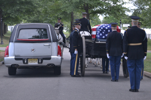 A photo of a hearse and flag-draped casket at Arlington Cemetery